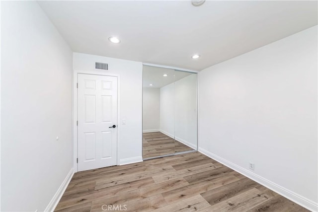 spare room featuring baseboards, wood finished floors, visible vents, and recessed lighting