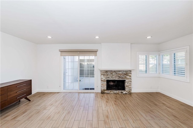 unfurnished living room with light wood-style flooring, a fireplace, baseboards, and recessed lighting