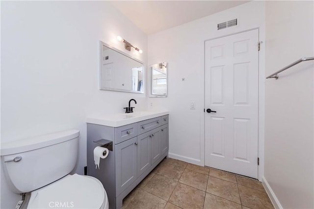 bathroom featuring toilet, vanity, baseboards, visible vents, and tile patterned floors