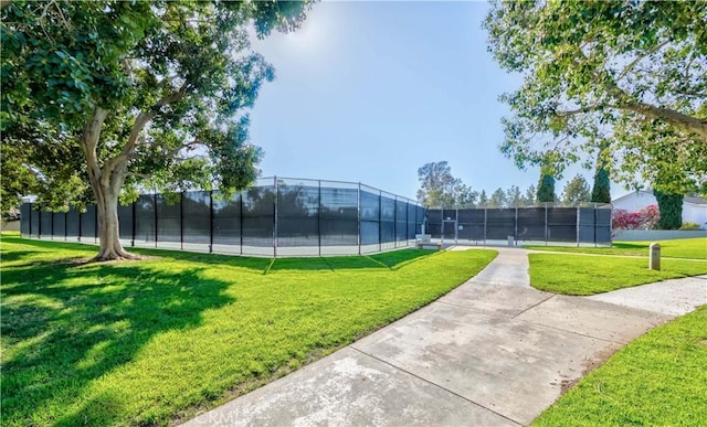 view of home's community with a tennis court, a lawn, and fence