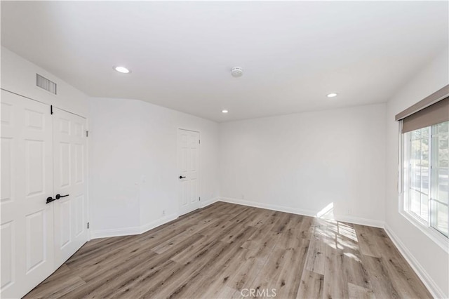 empty room with recessed lighting, baseboards, visible vents, and light wood finished floors