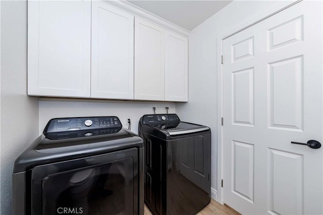 washroom with cabinet space, light wood-style floors, and washing machine and clothes dryer