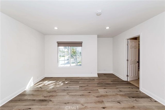 empty room with recessed lighting, wood finished floors, and baseboards