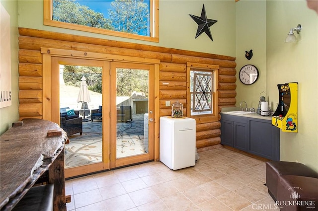 doorway to outside with french doors, a sink, and a high ceiling