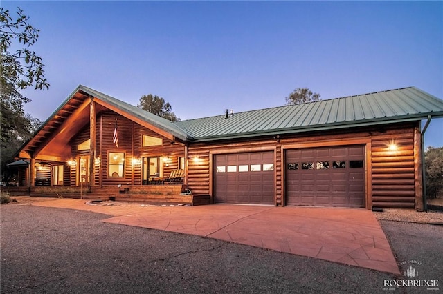 log home featuring a garage, metal roof, a porch, and concrete driveway