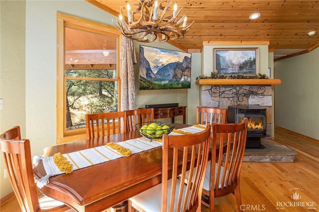 dining room with baseboards, wooden ceiling, wood finished floors, a stone fireplace, and recessed lighting