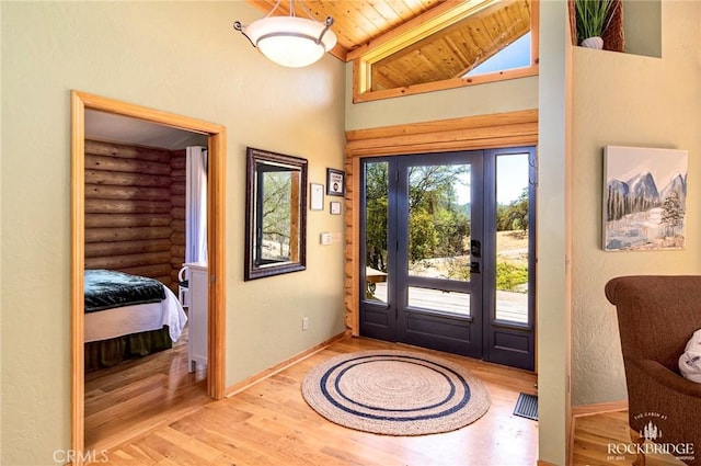 foyer entrance featuring rustic walls, wood ceiling, baseboards, and wood finished floors