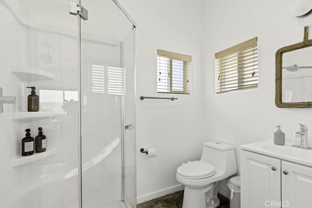 bathroom with toilet, a stall shower, baseboards, and vanity