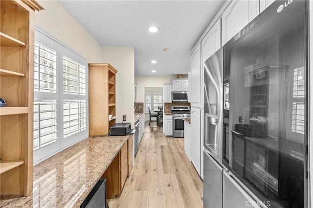 kitchen featuring white cabinets, light stone counters, stainless steel appliances, light wood-style floors, and open shelves