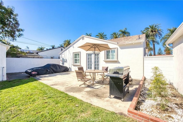 back of property featuring french doors, a yard, stucco siding, a patio area, and a fenced backyard