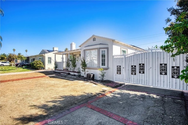 view of front of home with a fenced front yard, a gate, a porch, and stucco siding