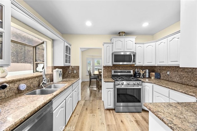 kitchen with light wood-type flooring, appliances with stainless steel finishes, decorative backsplash, and a sink