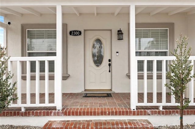 view of exterior entry featuring covered porch and stucco siding