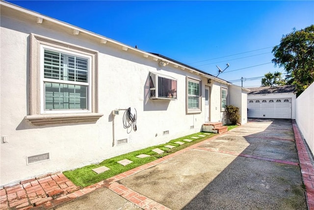 view of property exterior featuring crawl space, stucco siding, a detached garage, and an outdoor structure