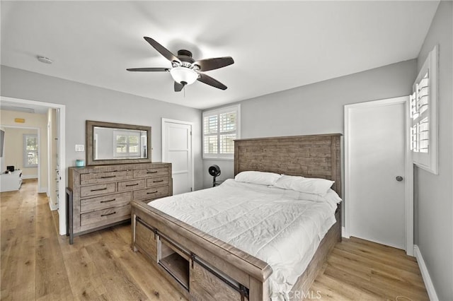 bedroom featuring light wood-style floors, multiple windows, and baseboards