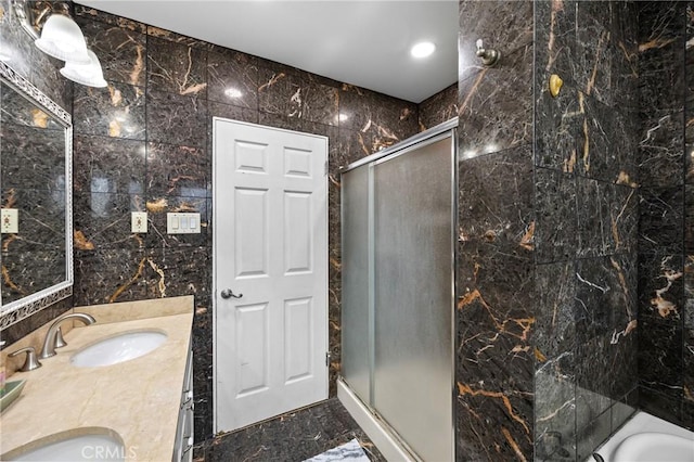 bathroom featuring a sink, tile walls, marble finish floor, double vanity, and a stall shower