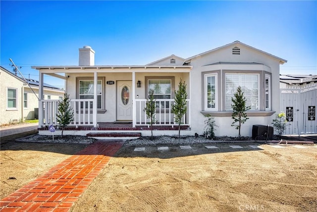 bungalow-style house with a porch, a chimney, and stucco siding