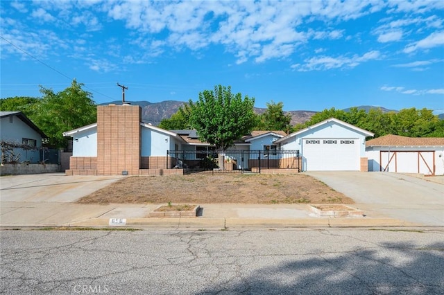 ranch-style home featuring driveway, a garage, solar panels, a fenced front yard, and a mountain view