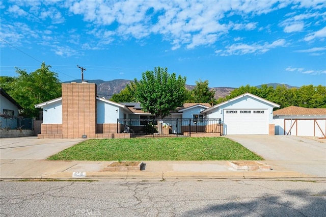 single story home with a chimney, a front lawn, a garage, a fenced front yard, and a mountain view