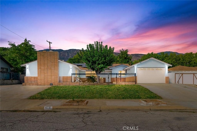 ranch-style home with a fenced front yard, a mountain view, a chimney, and driveway