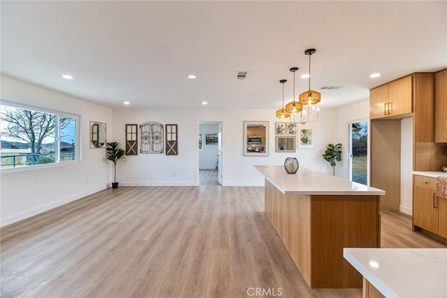 kitchen featuring light wood finished floors, a kitchen island, visible vents, and light countertops