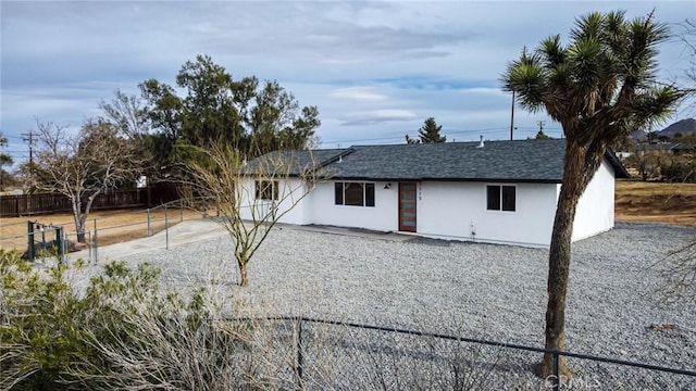 view of front of property with roof with shingles, fence, and stucco siding