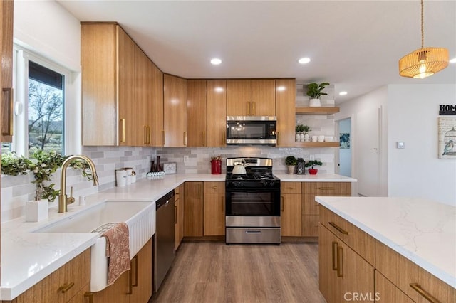 kitchen featuring light wood finished floors, tasteful backsplash, appliances with stainless steel finishes, open shelves, and a sink