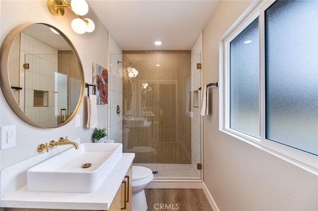 bathroom with vanity, a stall shower, wood finished floors, and toilet