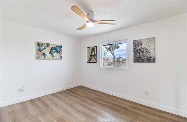 unfurnished room featuring light wood finished floors, a ceiling fan, and baseboards