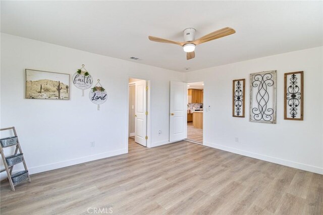 empty room featuring ceiling fan, light wood-type flooring, visible vents, and baseboards