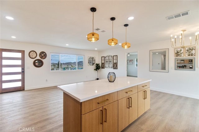 kitchen with a kitchen island, visible vents, and light wood-style floors