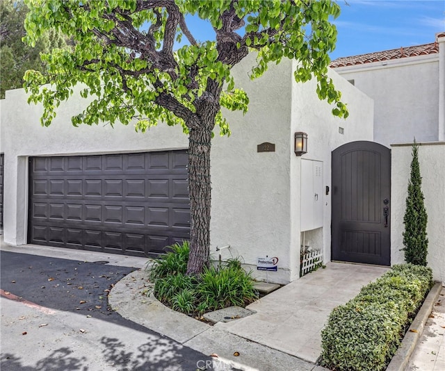 doorway to property with a garage and stucco siding