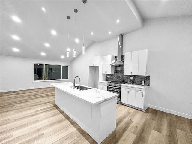 kitchen with stainless steel range oven, wall chimney range hood, white cabinetry, and light wood-style floors