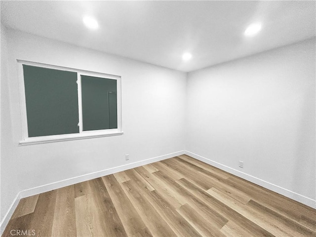 spare room with baseboards, wood finished floors, and recessed lighting