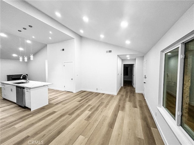 kitchen with a sink, visible vents, vaulted ceiling, dishwasher, and light wood finished floors