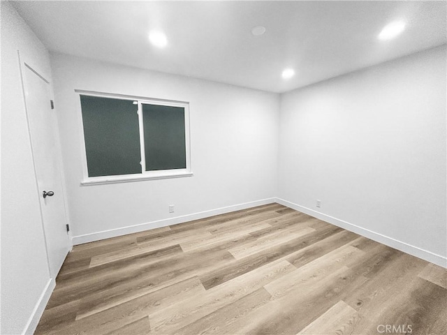 spare room with recessed lighting, baseboards, and wood finished floors