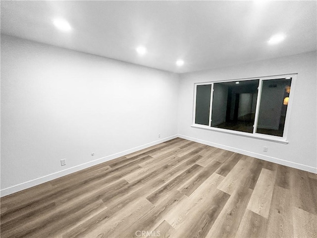 spare room featuring recessed lighting, baseboards, and wood finished floors