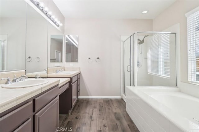 full bathroom featuring double vanity, a stall shower, a garden tub, and a sink