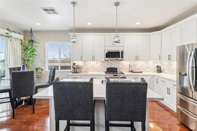 kitchen with visible vents, a kitchen bar, appliances with stainless steel finishes, and light countertops