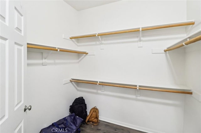 walk in closet with dark wood-style flooring