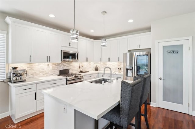 kitchen with decorative light fixtures, a breakfast bar, appliances with stainless steel finishes, dark wood-style floors, and a sink