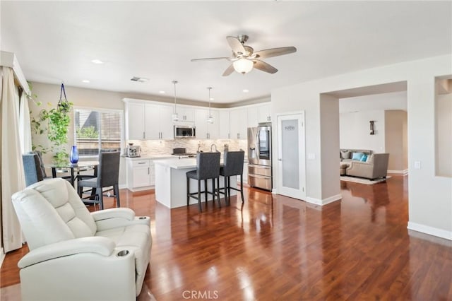 living area with visible vents, baseboards, ceiling fan, dark wood finished floors, and recessed lighting