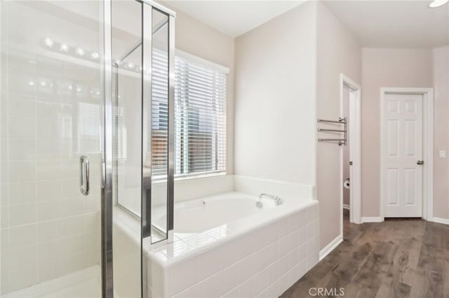 full bath with a stall shower, baseboards, a garden tub, and wood finished floors