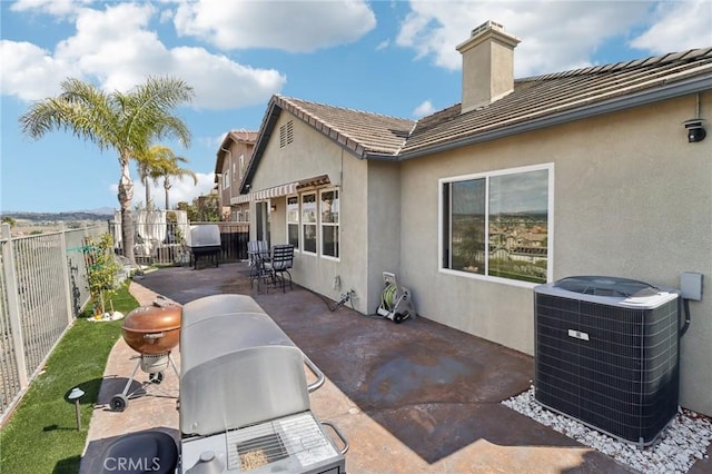 rear view of property featuring a fenced backyard, stucco siding, central air condition unit, a tiled roof, and a patio area