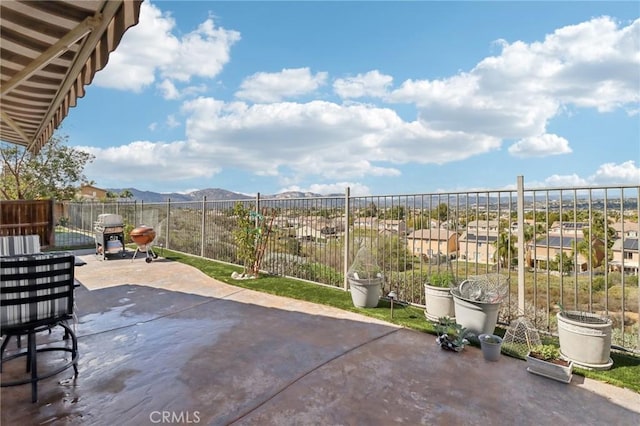 view of patio featuring a mountain view, a grill, and fence