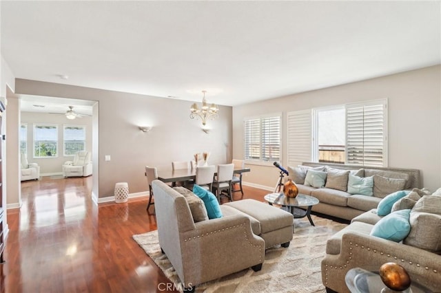 living room with a chandelier, baseboards, and wood finished floors