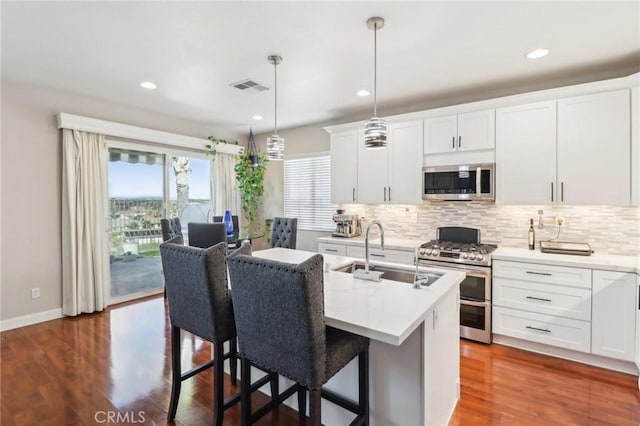 kitchen featuring visible vents, a sink, decorative backsplash, light countertops, and stainless steel appliances