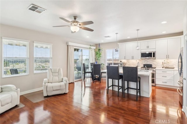 kitchen featuring stainless steel appliances, dark wood-type flooring, visible vents, and open floor plan