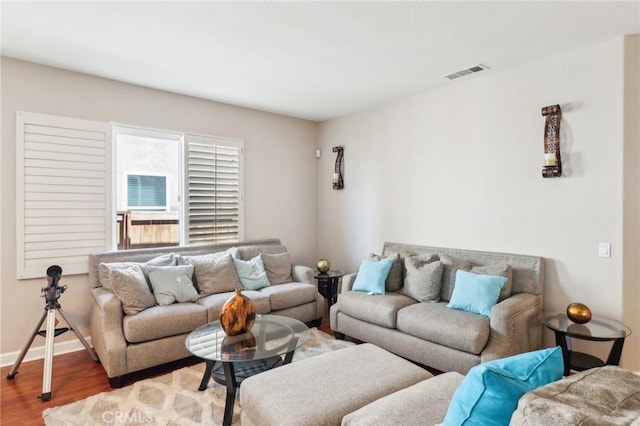 living room with visible vents, baseboards, and wood finished floors