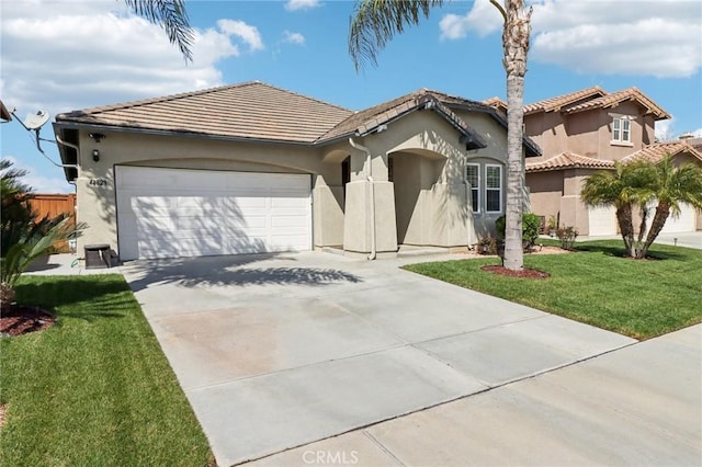 view of front facade with a tiled roof, concrete driveway, a front yard, stucco siding, and a garage